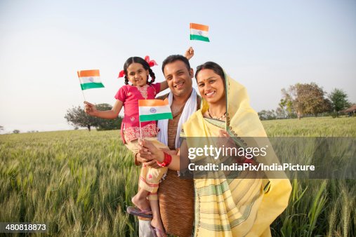 Farmer family standing in a green wheat field in India